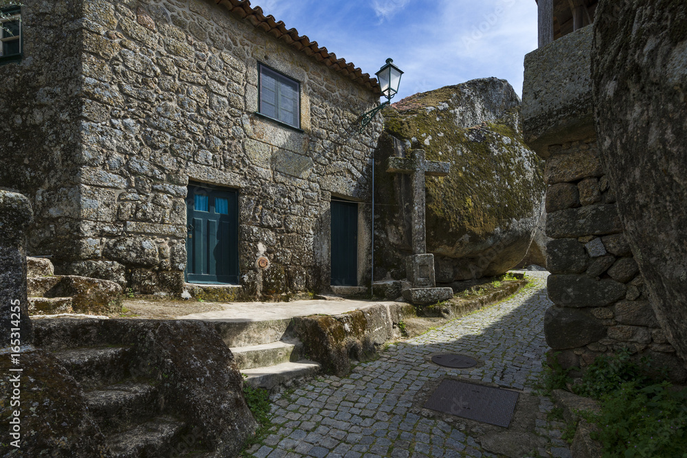 Narrow cobblestone street between bolders and houses in the historic village of Monsanto in Portugal; Concept for travel in Portugal