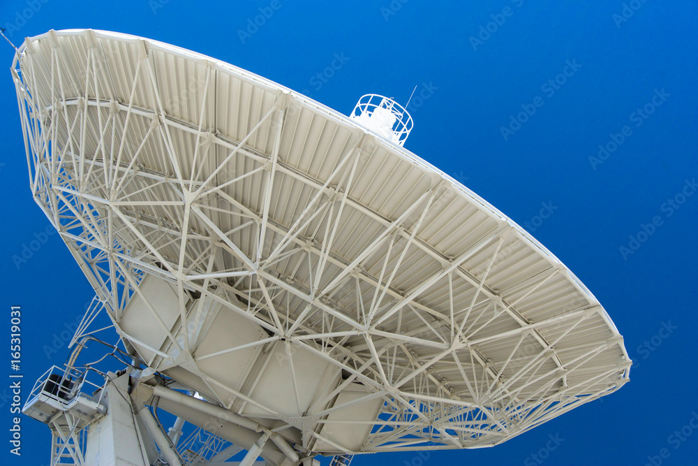 white satellite dish and radio telescope with a blue sky behind