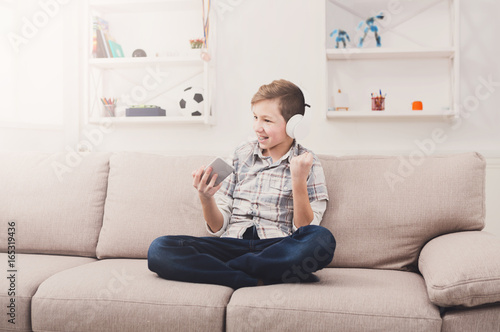 Happy teenage boy in headphones with mobile at home
