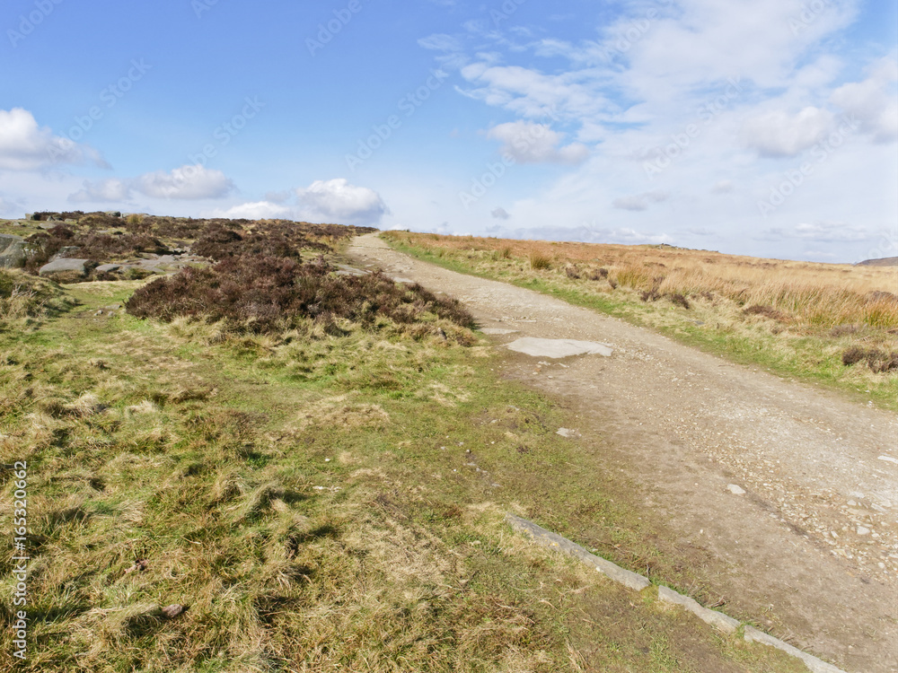 High in the Peak District a well trodden path bordered by ferns, grass and bracken winds gently uphill