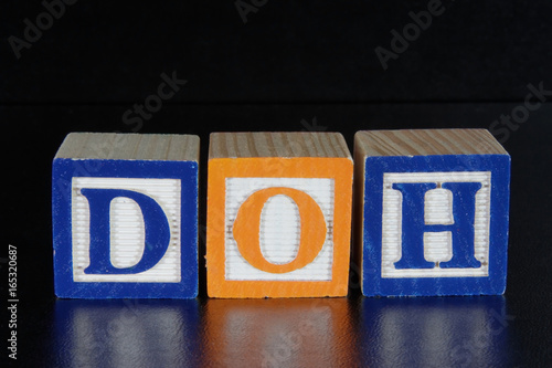 The concept DOH spelled with toy alphabet blocks on a black background with foreground reflection. photo