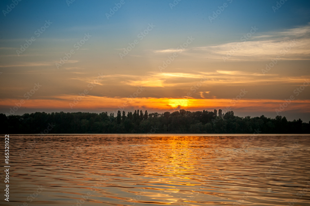 beautiful majestic sunset on the background of the river bank with some unrecognizable swimming people in Kiev Ukraine beautiful majestic sunset on the background of the river bank with some unrecognizable swimming people in Kiev Ukraine