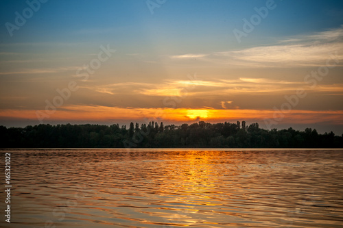 beautiful majestic sunset on the background of the river bank with some unrecognizable swimming people in Kiev Ukraine © iamjura