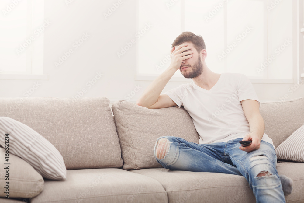 Young man watching television, using remote control Young man watching television, using remote control
