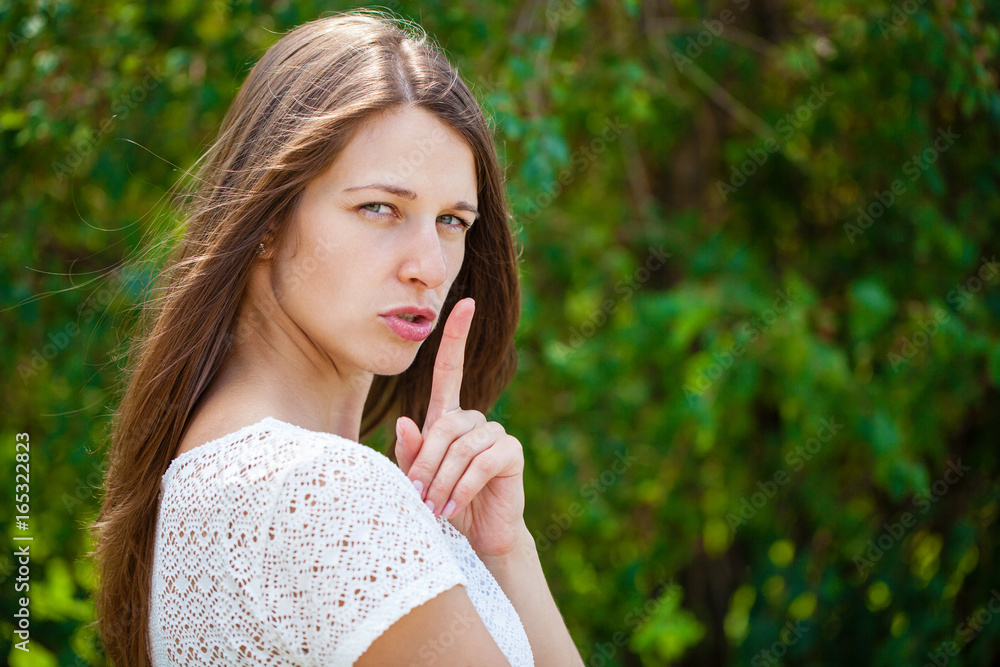 Young beautiful brunette woman has put forefinger to lips as sign of silence Young beautiful brunette woman has put forefinger to lips as sign of silence