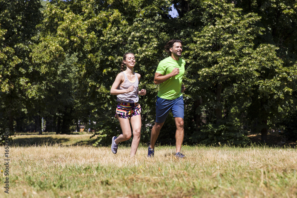 Obraz premium Young couple running in the park on a sunny day