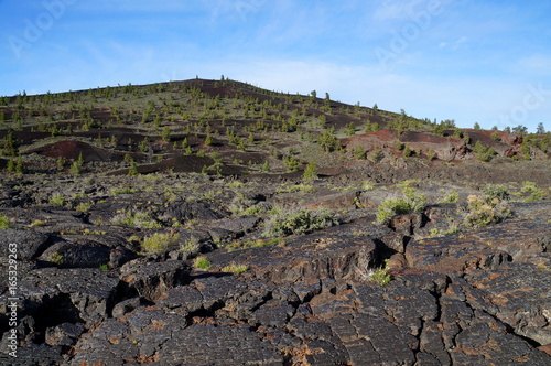Three types of black volcanic basalt rock: cinder cone, formed by small porous pebbles, relatively smooth pahoehoe lava, aa lava chunks of relatively angular pieces of lava. Craters of the Moon.