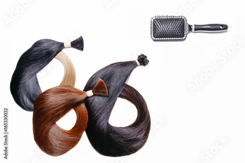 hair extensions of three colors on a white background with comb. copyspace top view. photo