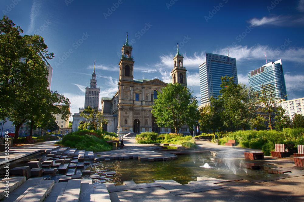Naklejka premium Plac Grzybowski w Warszawie w nowym widoku z ciekawą fontanną, kościołem Ducha Świętego i Pałacem Kultury i Nauki