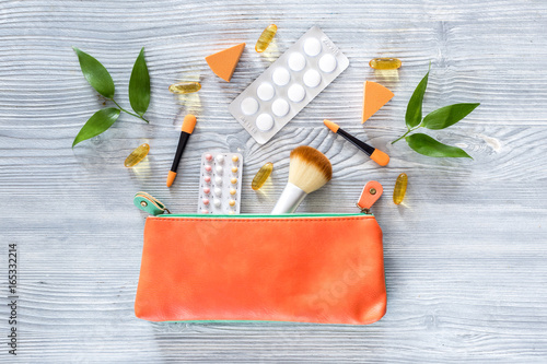 Cosmetic bag with contraceptives and pills on wooden table background top view copyspace photo