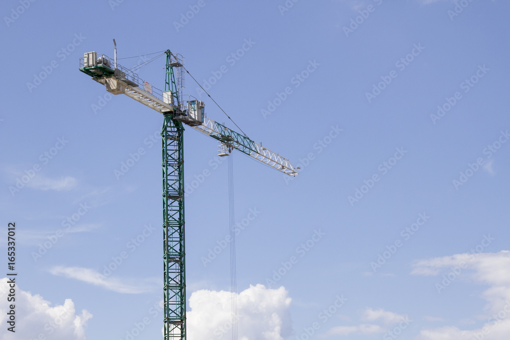 Green tower crane against the blue sky