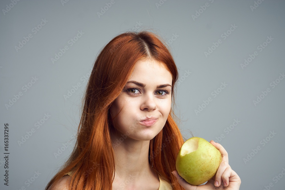 Beautiful young woman on a gray background holding an apple Beautiful young woman on a gray background holding an apple