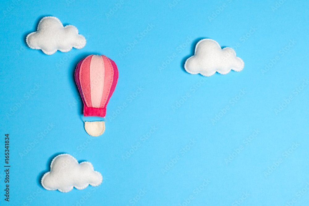 Obraz premium Hot air balloon in blue sky with clouds, frame, copyspace. Hand made felt toys.