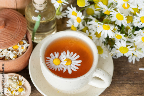 cup of herbal chamomile tea with fresh daisy flowers on wooden background. doctor treatment and prevention of immune concept  medicine - folk  alternative  complementary  traditional medicine 
