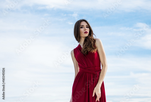 Beautiful girl in a red dress on the beach. Concept of femininity, harmony.