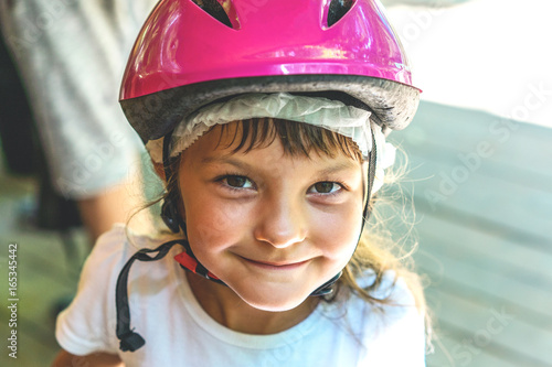 Portrait of a smiling girl child 5 years in a pink bicycle helmet close-up on the street