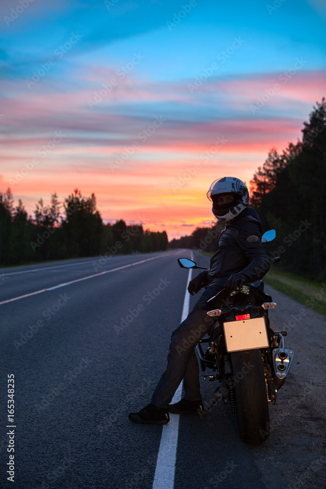 Fototapeta premium Tired motorcyclist resting on roadside when travel on motorcycle at night time