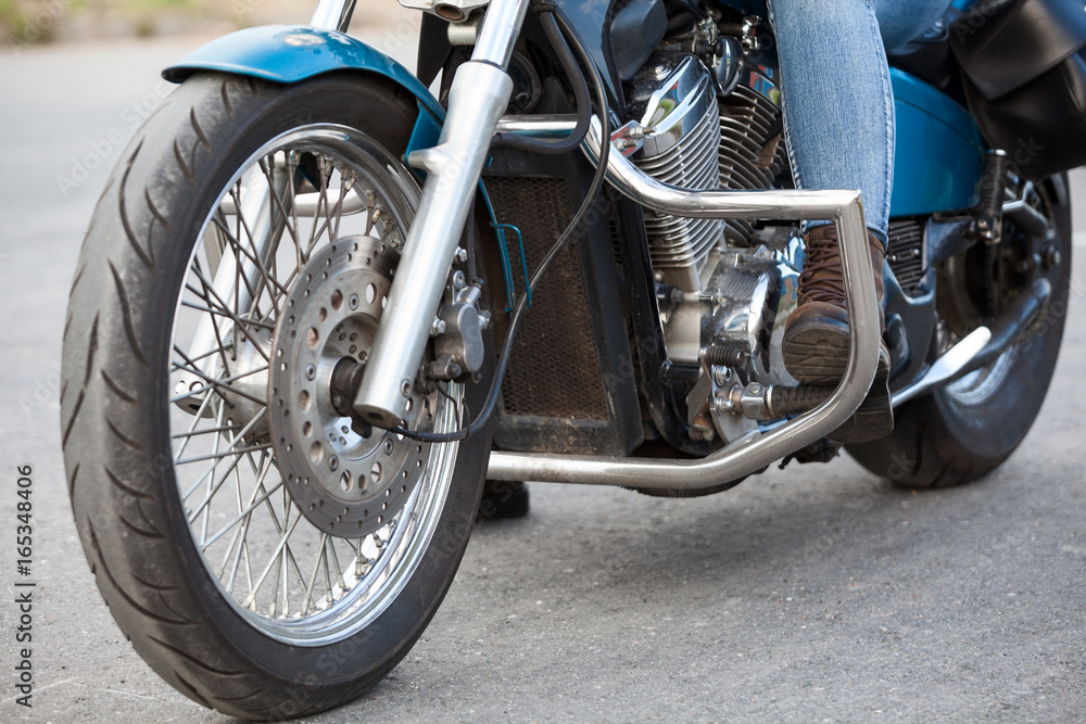 Obraz premium Close-up, front view at motorcyclist foot with protective brown boot on the stands of motorbike with chrome protective arcs