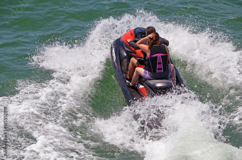 Couple riding tandem on a speeding jet ski on the florida intra-coastal waterway near Miami Beach.