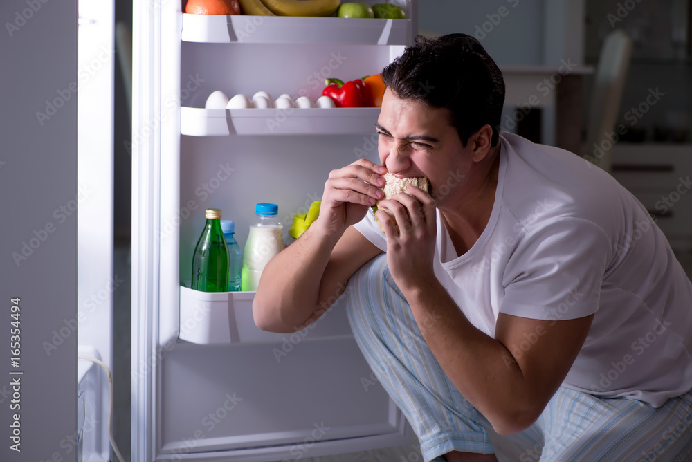 Man at the fridge eating at night Man at the fridge eating at night