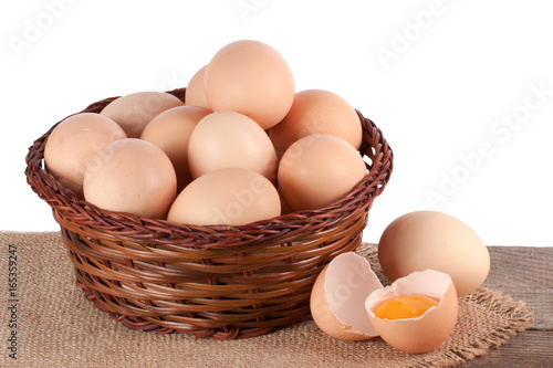 eggs on a wooden table in a wicker basket on a white background