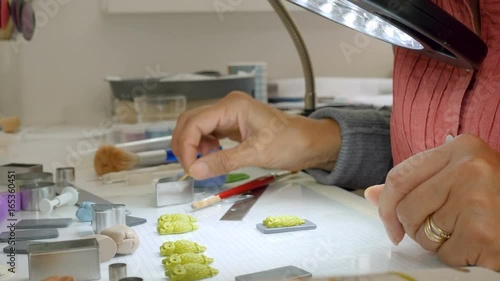 elderly woman expertly crafts polymerclay owl shaped buttons for her arts and crafts project while working in her studio photo