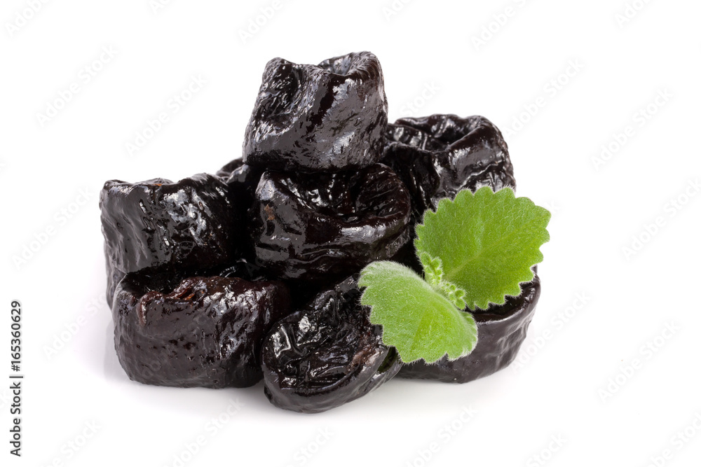 heap of dried plums or prunes with a mint leaf isolated on white background