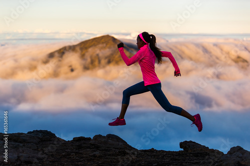 Fitness run athlete runner girl running at sunset on mountain trail. Scenic landscape cold clouds weather. Woman sprinting training cardio in nature outdoors.