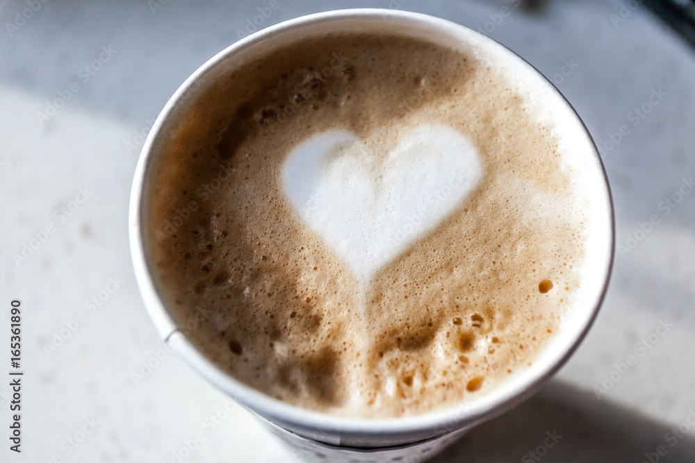 Coffee latte in a plastic mug, artistic heart pattern on top Coffee latte in a plastic mug, artistic heart pattern on top