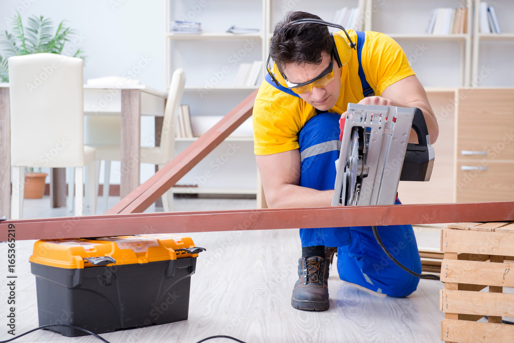 Repairman carpenter cutting sawing a wooden plank with a circula Repairman carpenter cutting sawing a wooden plank with a circula