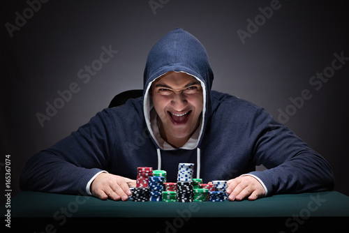 Tablou pe pânză Young man wearing a hoodie with cards and chips gambling