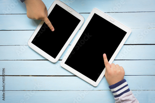 Children's hands using tablet computer on wooden blue table.Top view and zoom in