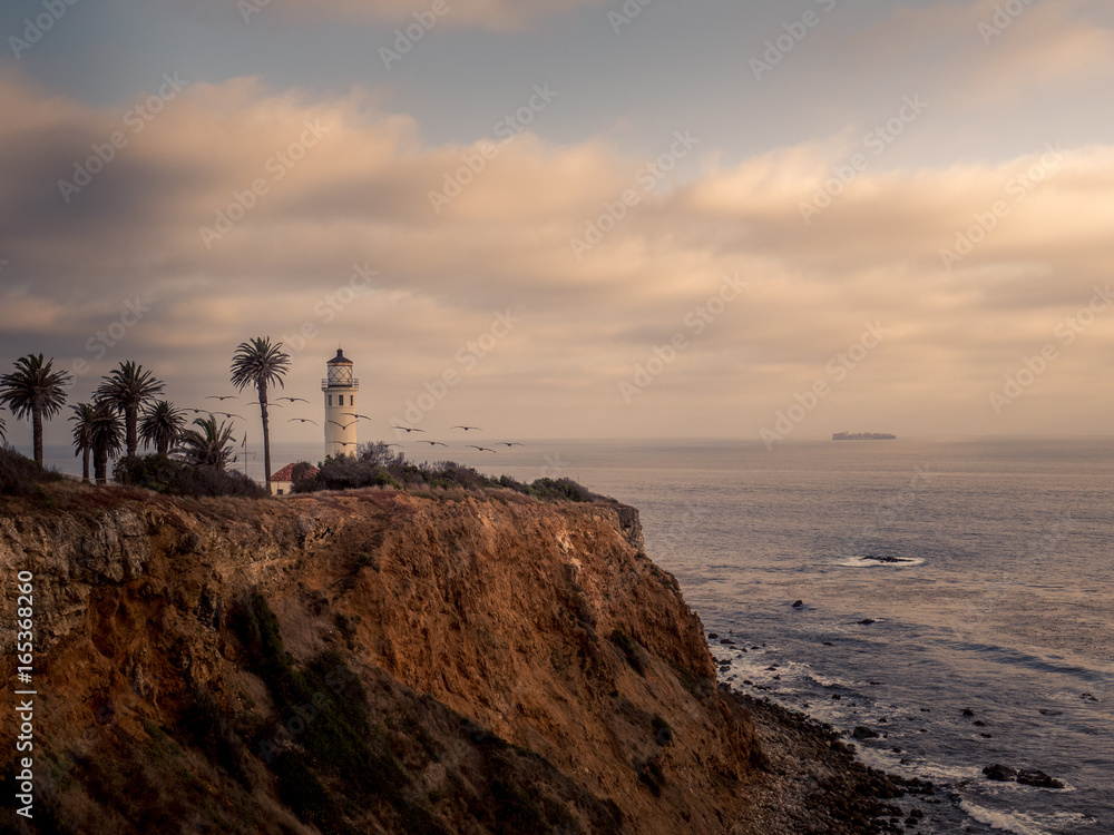 Lighthouse overlooking a sunset on the ocean