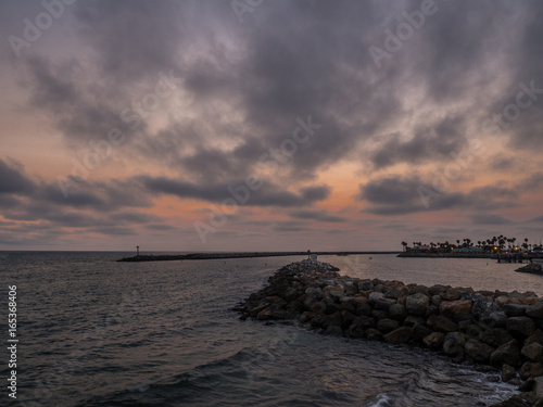 Partially cloudy sunset behind breakwater