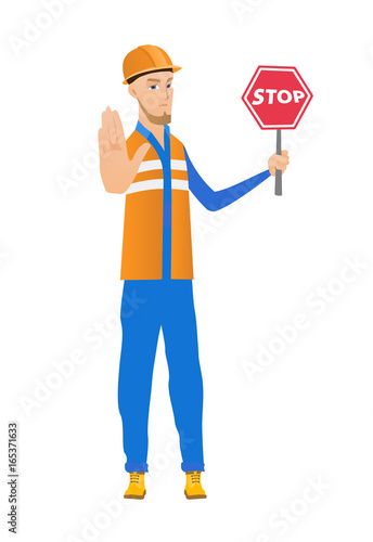Young caucasian builder holding stop road sign.