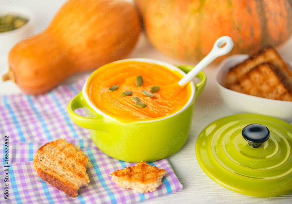creamy pumpkin soup topped with pumpkin seeds and bread in green bowl on napkin, concept of vegetarian food creamy pumpkin soup topped with pumpkin seeds and bread in green bowl on napkin, concept of vegetarian food
