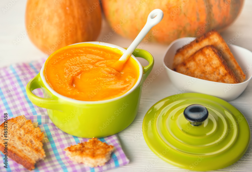 still life of creamy pumpkin soup and bread in green bowl on napkin still life of creamy pumpkin soup and bread in green bowl on napkin