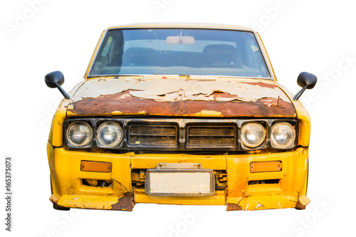 The front of the old yellow car rusting. Old car parked.