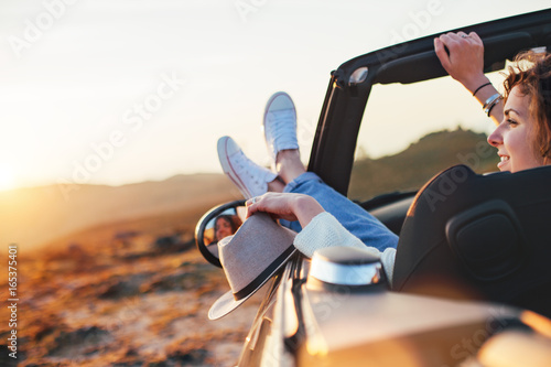 Pretty woman enjoys a sunset from a convertible