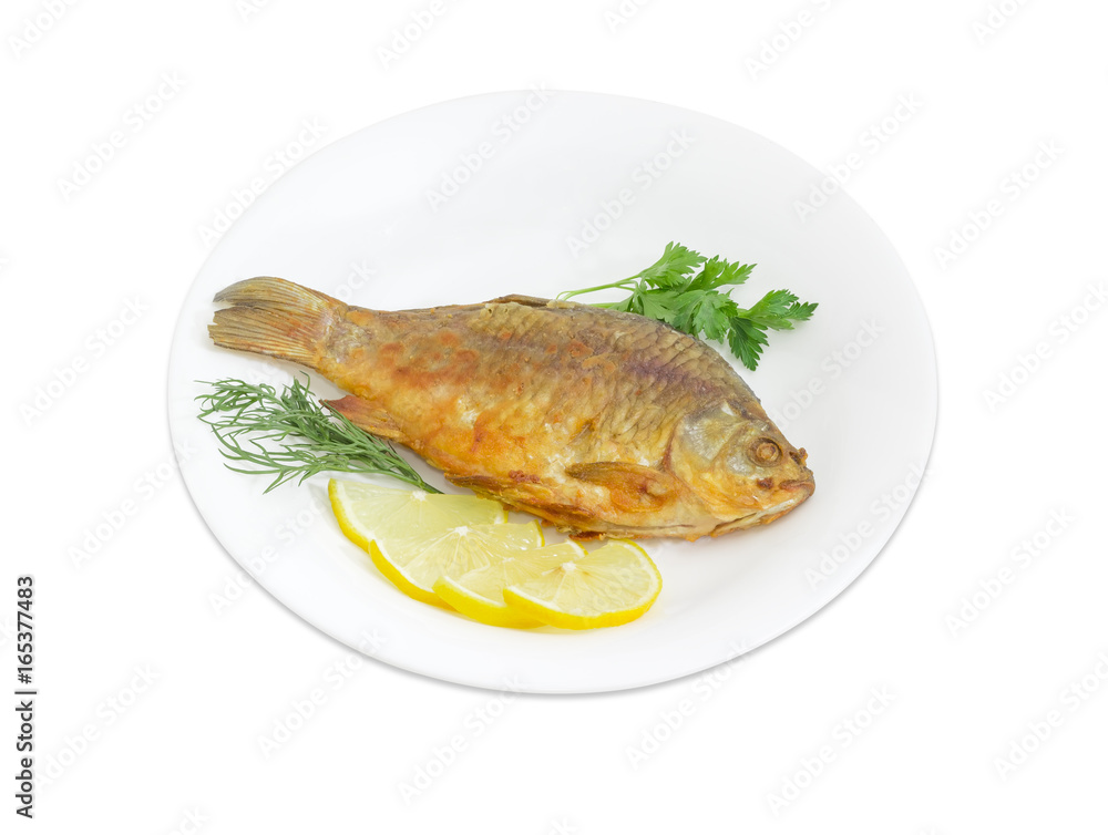 Fried crucian with lemon and potherb on white dish