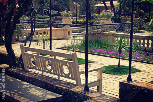 White wooden bench in a green blooming park.