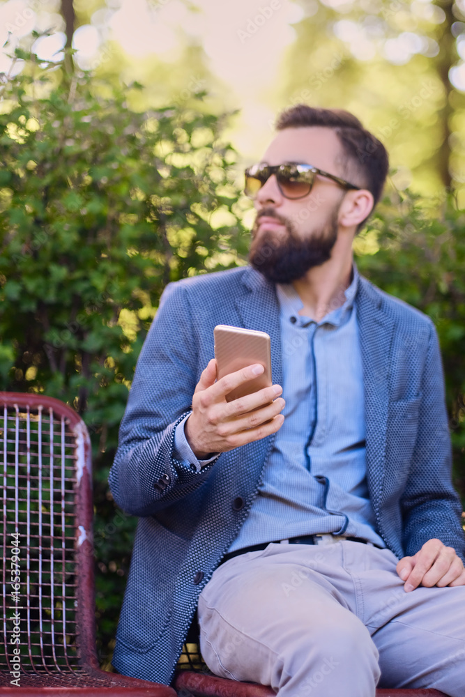 Stylish bearded male in a blue jacket using smartphone. Stylish bearded male in a blue jacket using smartphone.