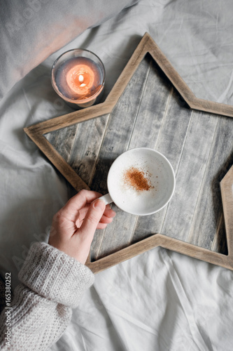 The girl is holding a cup of coffee on a tray