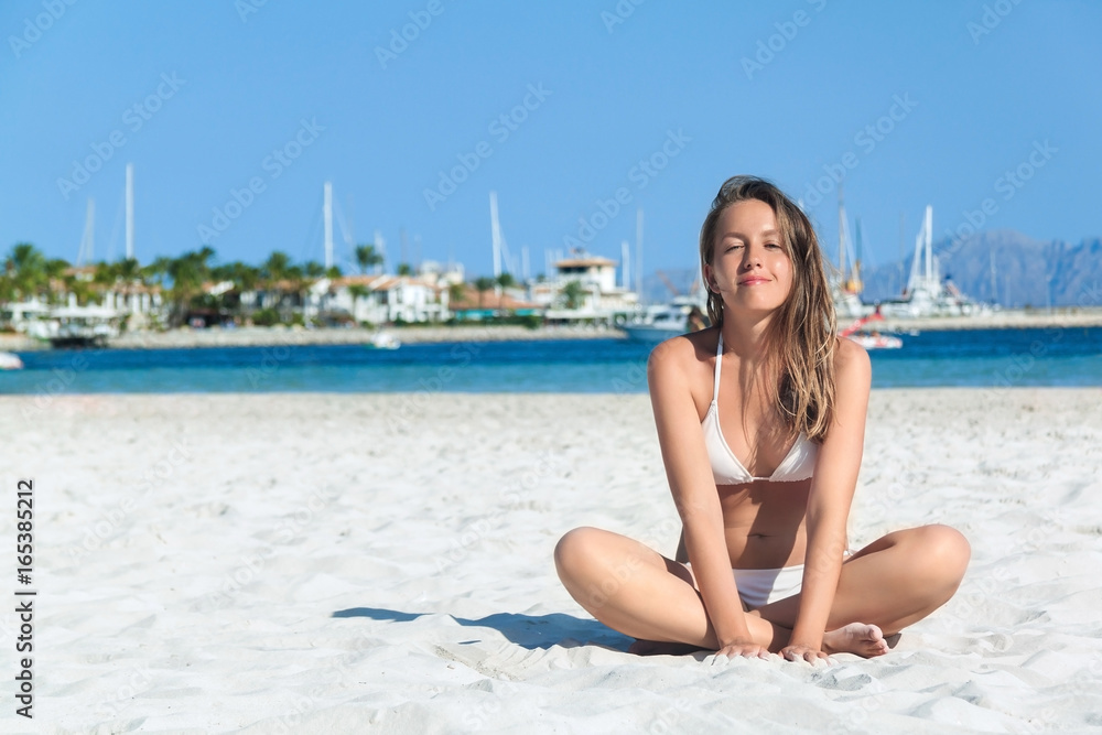 Young woman sitting on the white sand beach of Alcudia, Mallorca, Spain