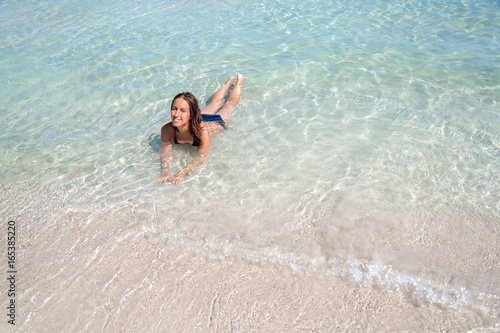 Young woman lying in clear sea water of the beautiful Alcudia beach in Mallorca, Spain © fischers
