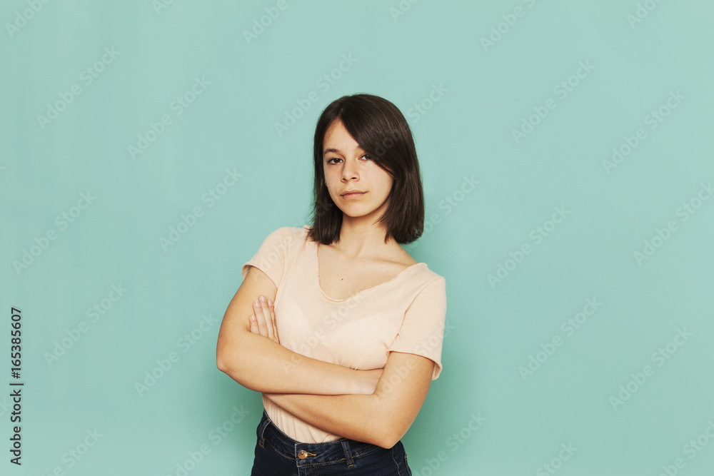 Portrait of confident girl standing with arms crossed against turquoise background Portrait of confident girl standing with arms crossed against turquoise background