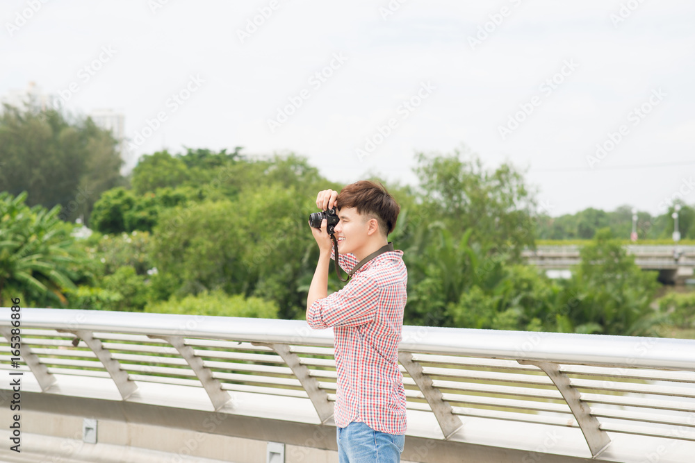 Young asian man taking a photo in city