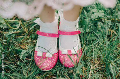 Baby pink shoes in the grass © Olha Cheverda