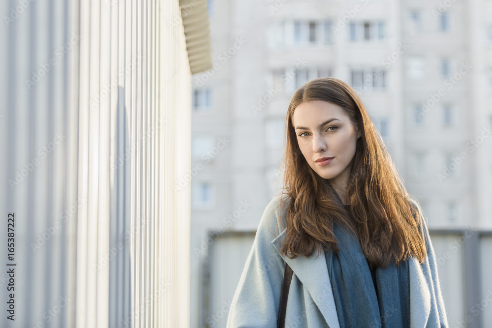 Portrait of young woman with long brown hair standing by wall in city Portrait of young woman with long brown hair standing by wall in city