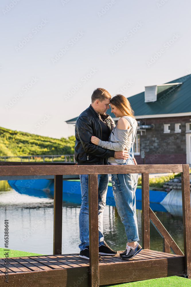 Happy and young pregnant couple hugging outdoors